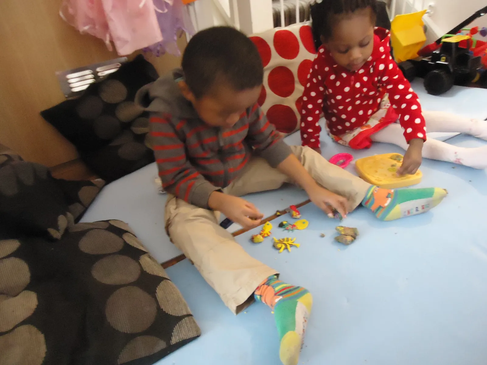 Two children playing with toys on floor cushions