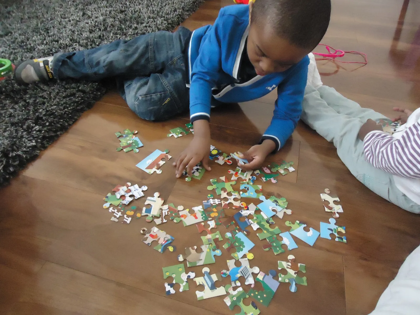 Two children completing a jigsaw puzzle together on the floor