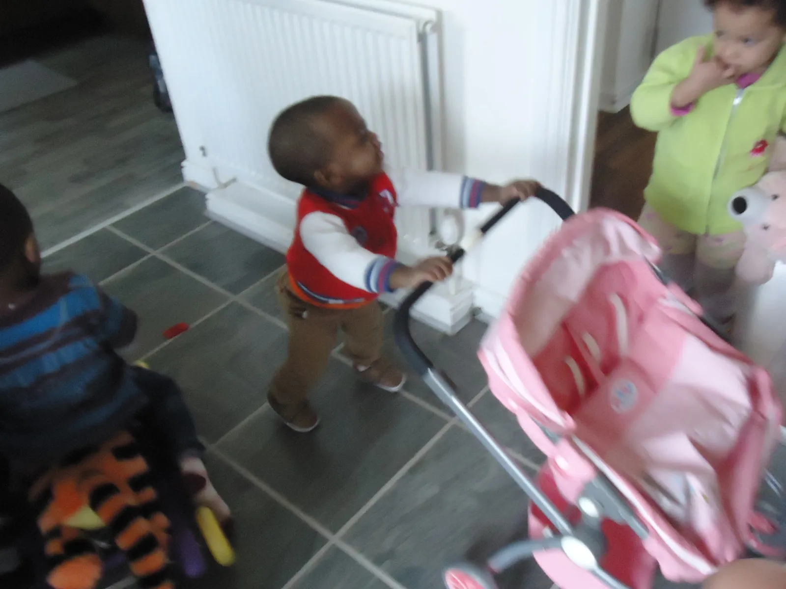 Toddler pushing a toy pram indoors